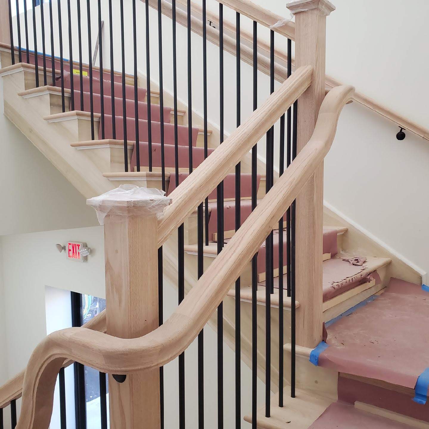 Custom stair and railing installation with oak handrail and black metal balusters